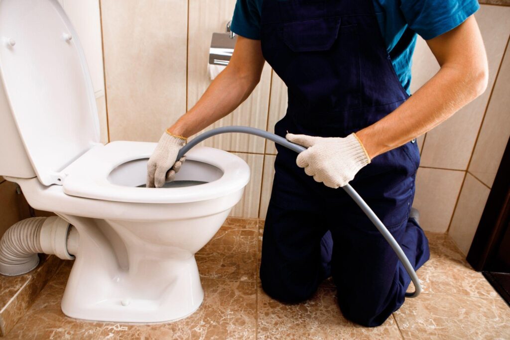 plumber unclogging blocked toilet with hydro jetting